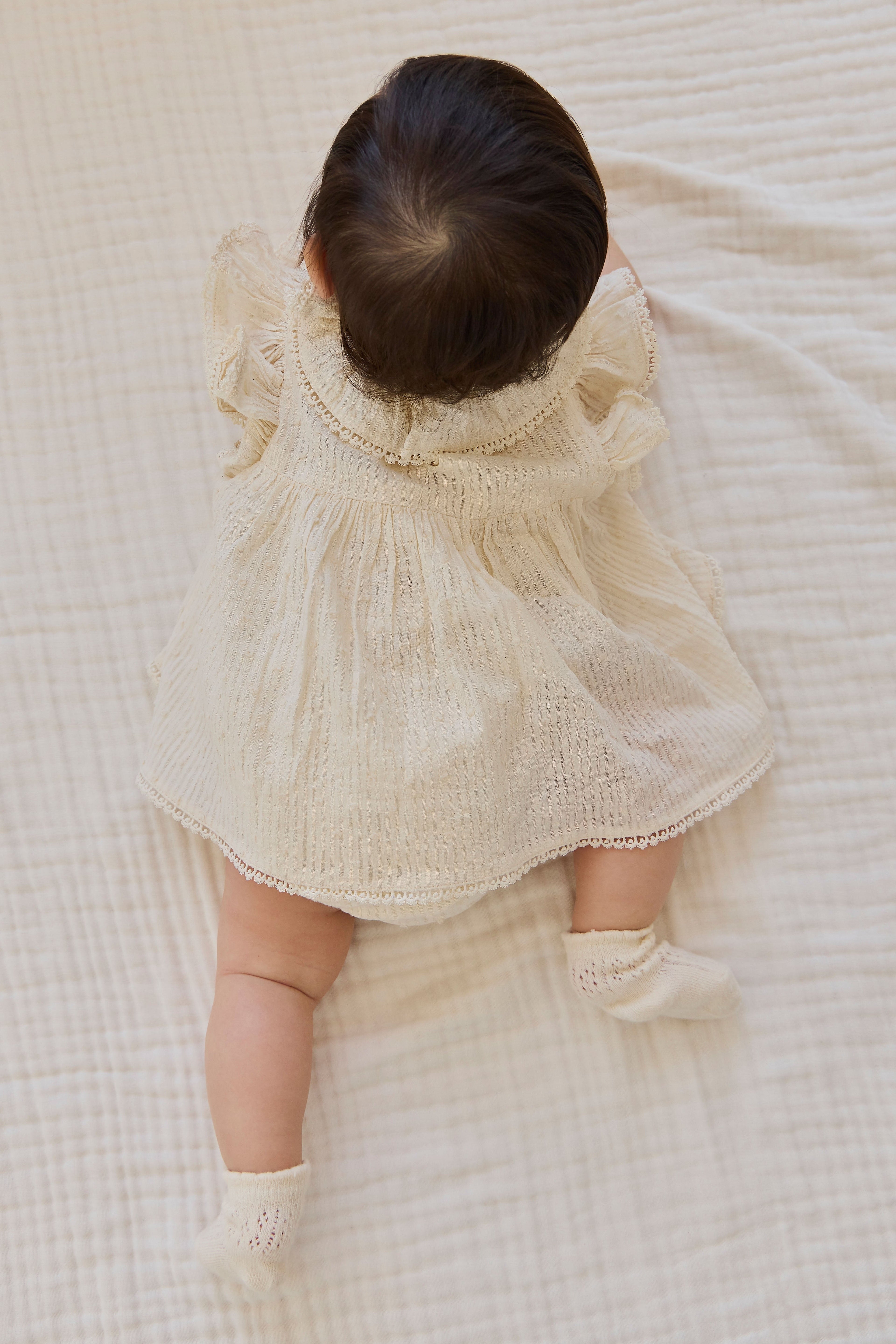 Combinaison bébé en mousseline de coton biologique unie parchemin romantique avec col volanté et manches flottantes 0-2 ans