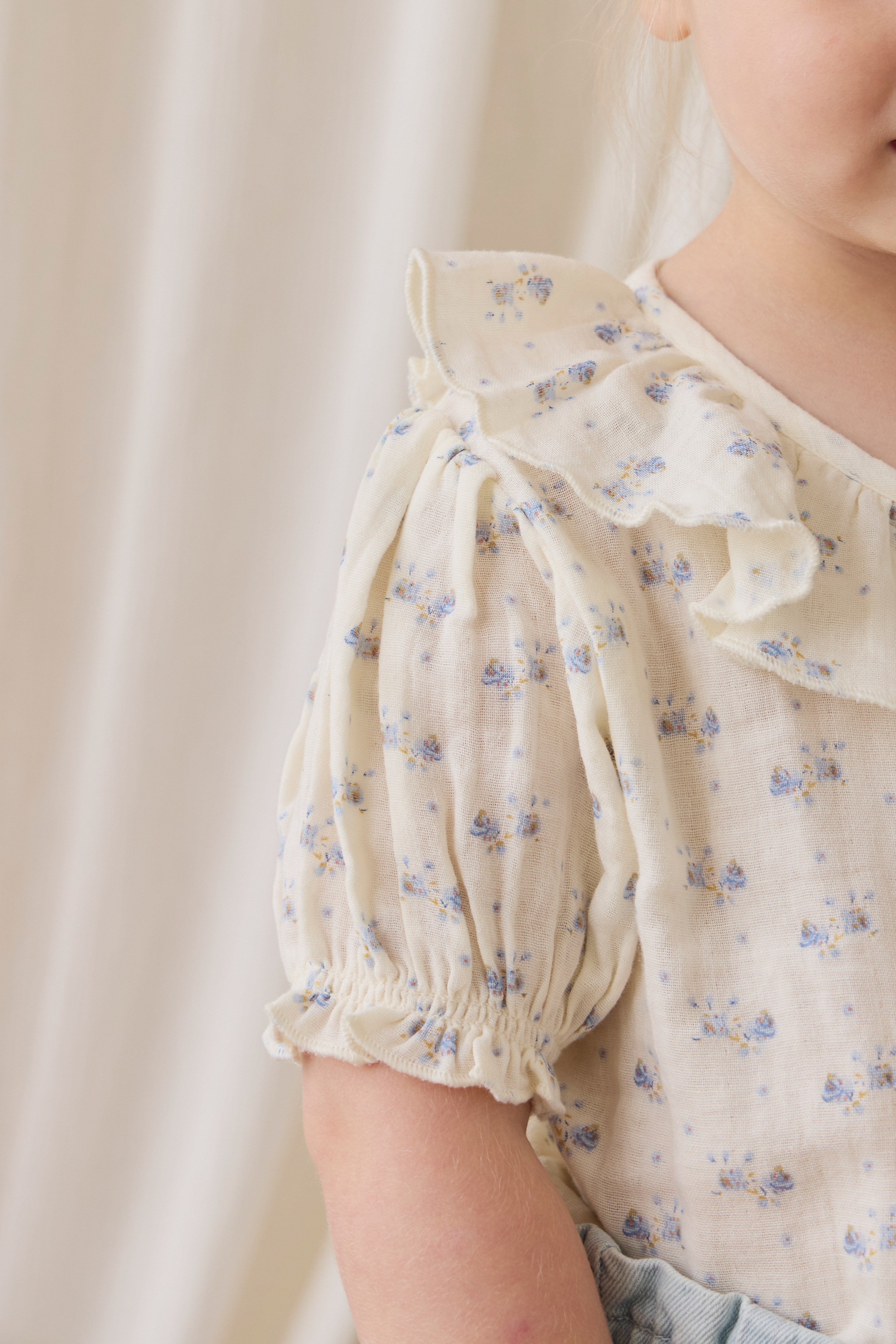 Haut en mousseline de coton biologique Molly Blue à fleurs délicates avec col à volants et manches bouffantes pour enfants de 0 à 10 ans